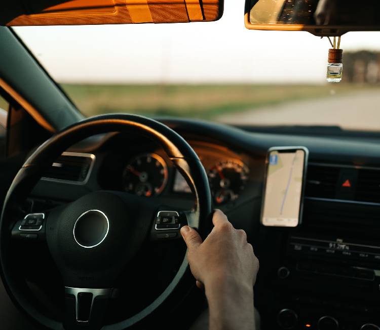 A hand holding a phone in a car coordinating volunteer activities